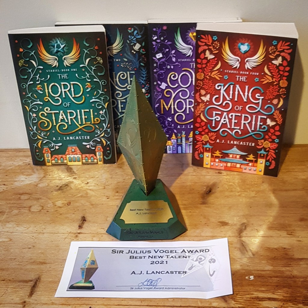 A gold and green trophy shaped like a diamond placed in front of the four books from the Stariel series.