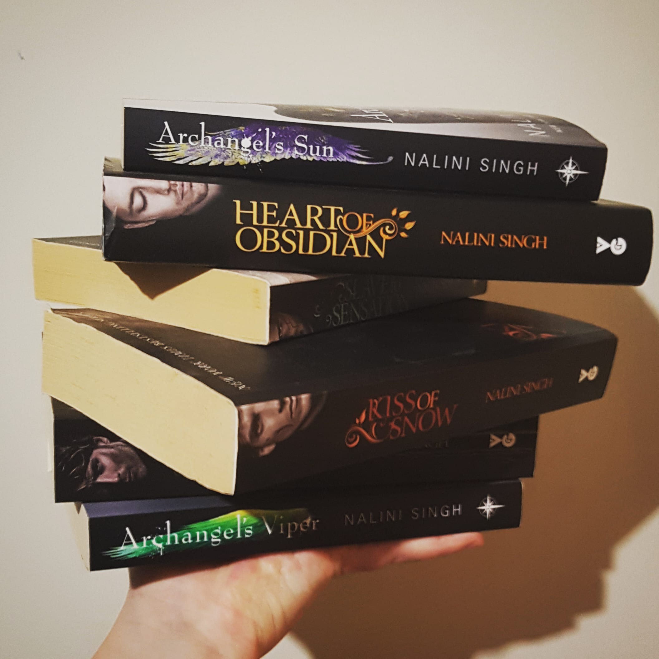 A hand supporting a stack of Nalini Singh books with black covers.